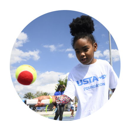 Young girl hitting a red ball tennis ball