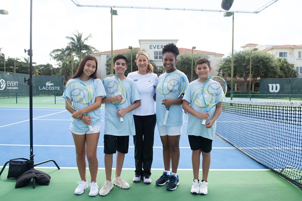 Chris Evert,, USTA Foundation chairperson since 2019., on a tennis court with youth tennis players smiling and posing with their racquets