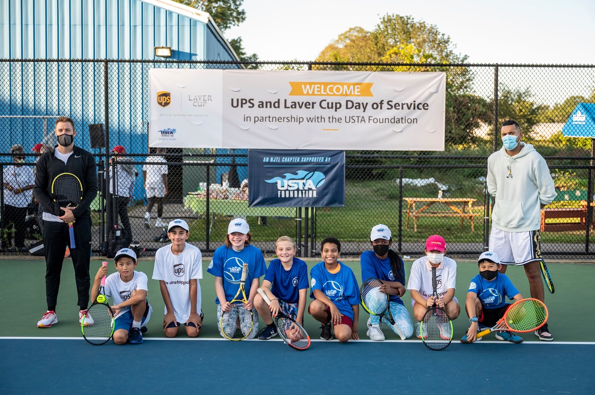 Kyrgios and Sock with kids from the Sportsmen's Tennis & Enrichment Center on a tennis court