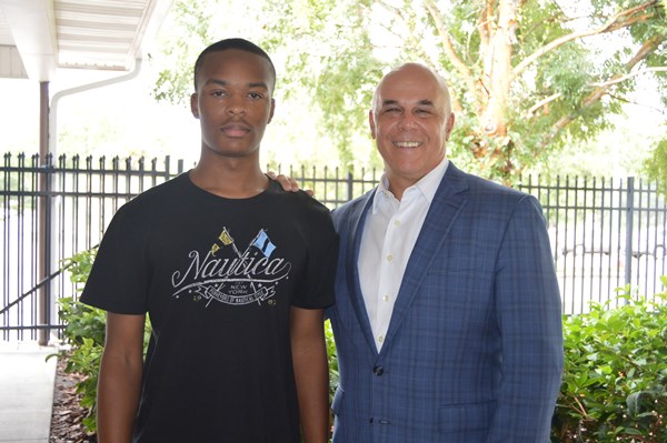Jabeiro Brown and his mentor Pat Geraghty smiling in front of a fence and trees