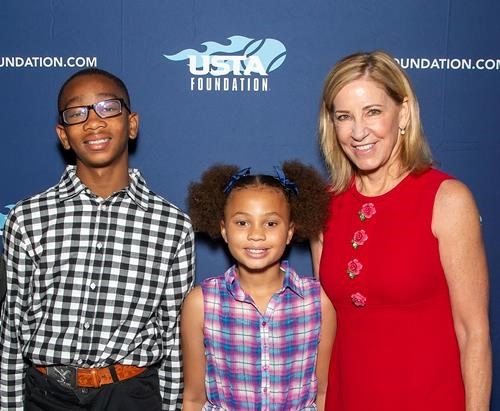 Chris Evert smiling with USTA Foundation/NJTL children in fron of a step-and-repeat