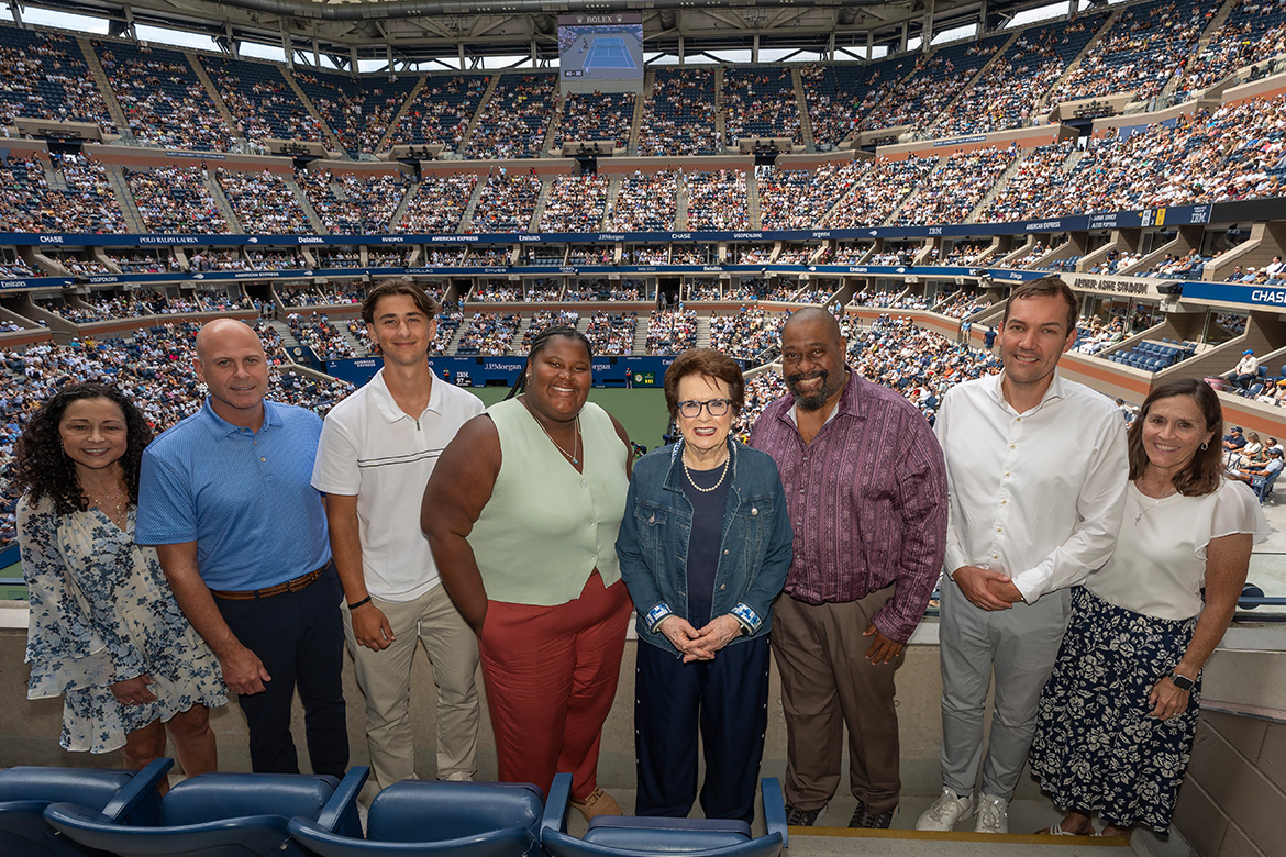 Eight people standing in a suite at Arthur Ashe Stadium during the US Open.