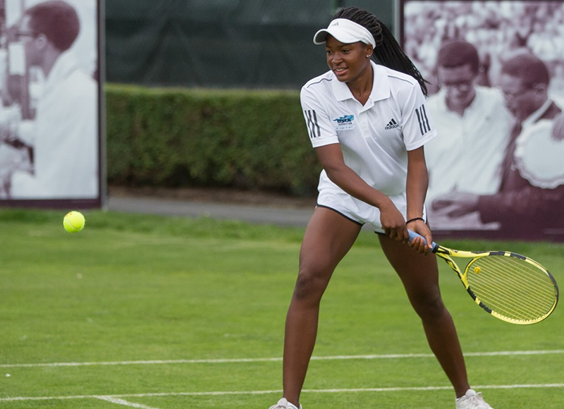 Student hitting ball on a grass court